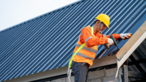 Maintenance Tips for Metal Buildings - man in construction gear working on metal building roof - jag metals llc